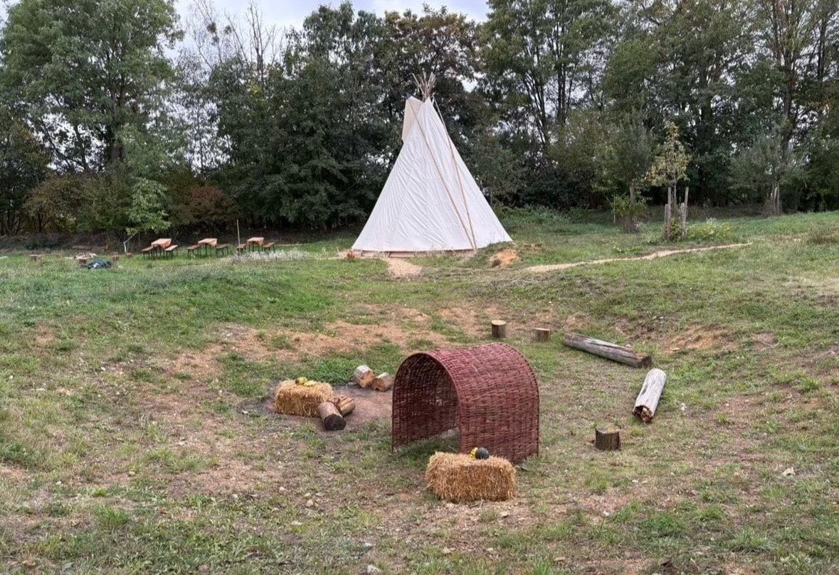 Naturplatz mit Tipi, Baumstämmen und Sitzgelegenheiten