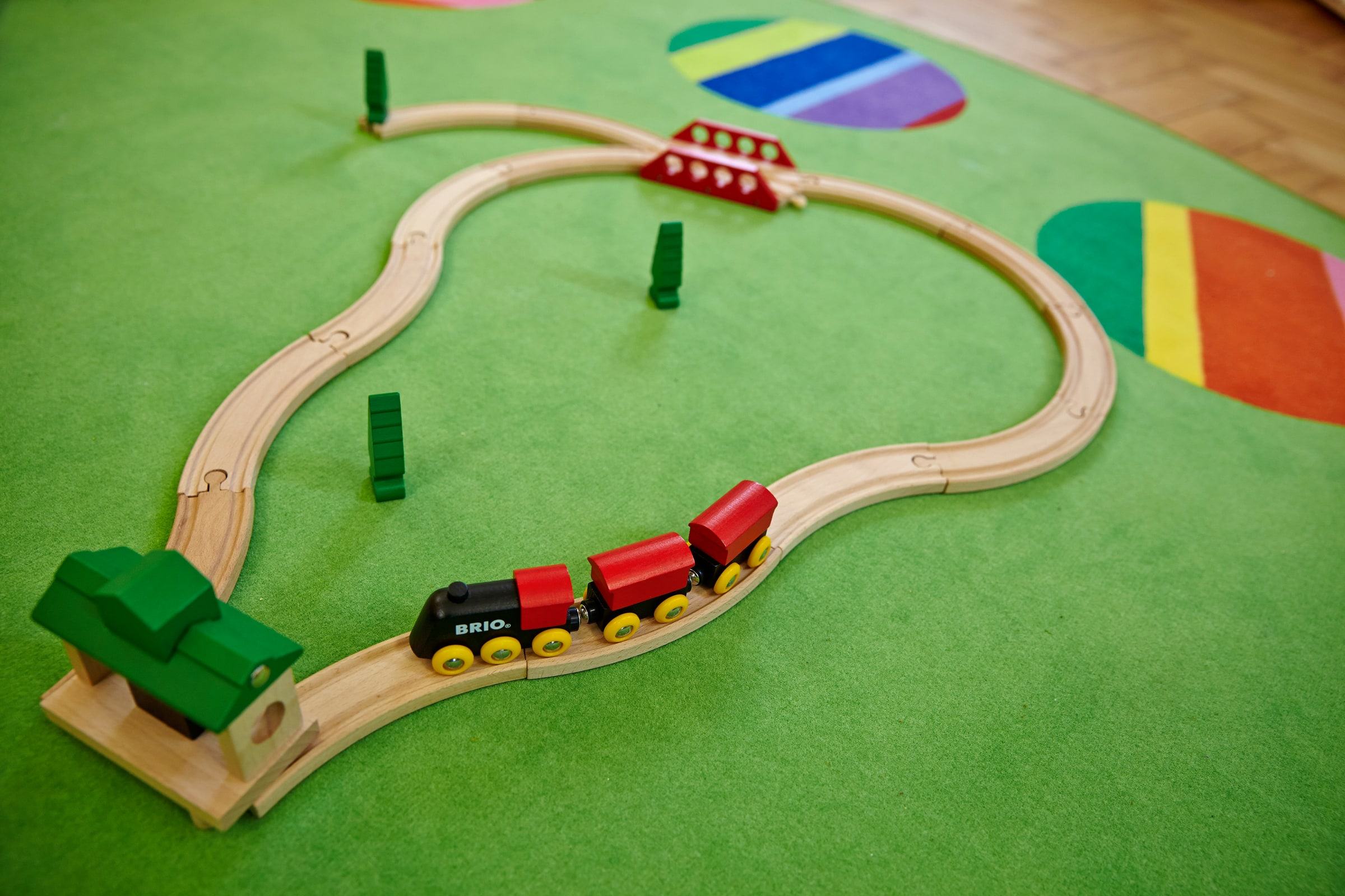 Hölzerne Spielzeugeisenbahn auf einem grünen Teppich